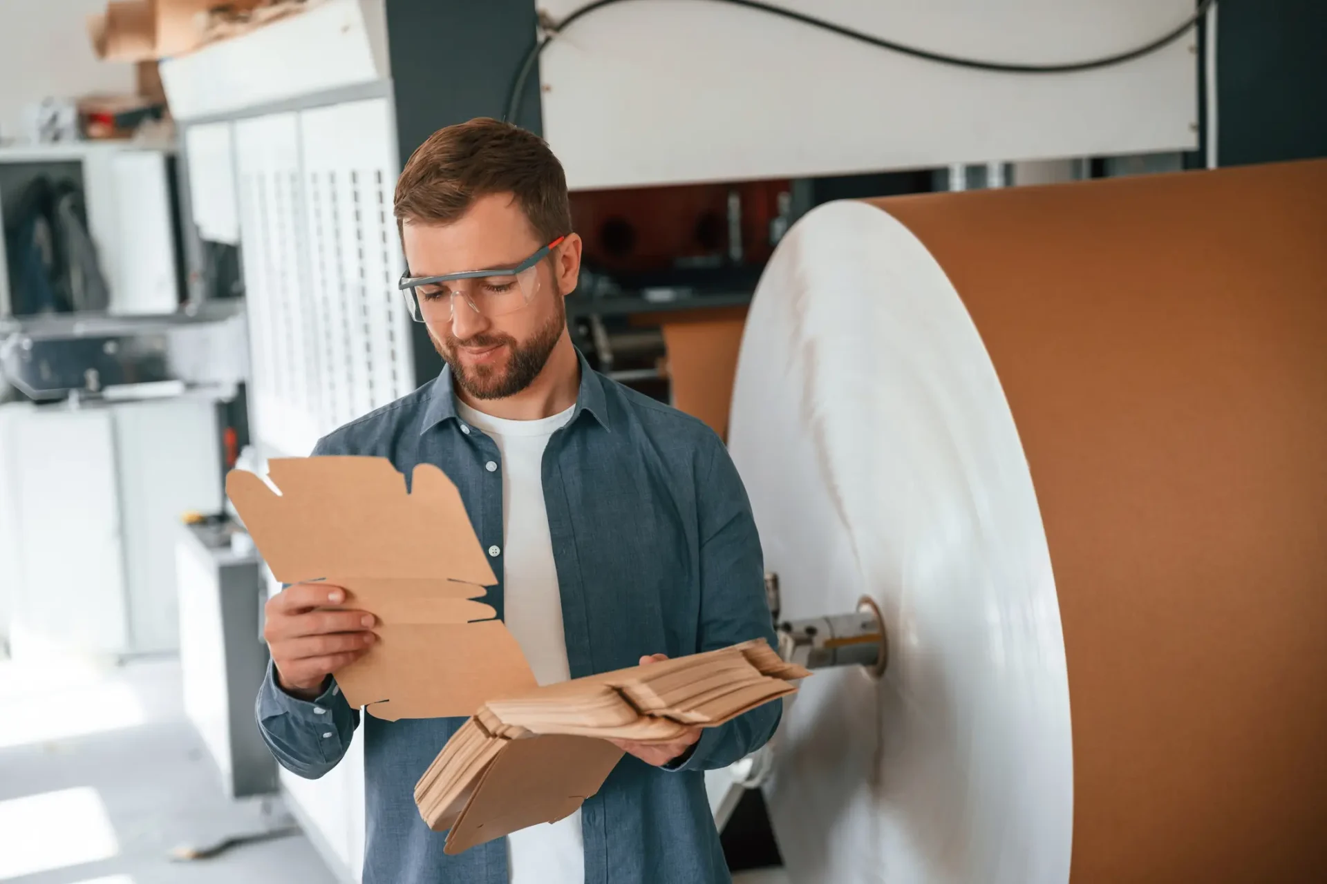 Man inspecting cardboard sheets in factory.